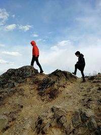 Two children walking on rocks against sky during autumn day