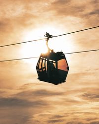 Low angle view of silhouette rope against orange sky