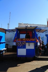 People at market stall against clear blue sky