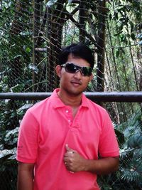 Portrait of young man wearing sunglasses standing in forest