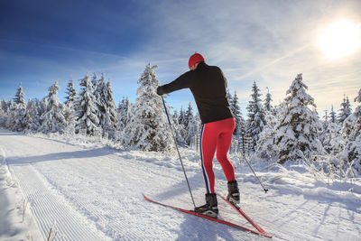 Man skiing on snow covered field against sky