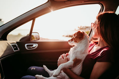 Woman with dog sitting in car