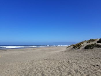 Scenic view of beach against clear blue sky