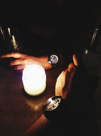 Midsection of person holding illuminated candles on table