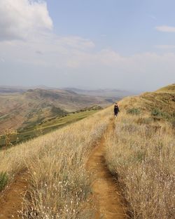 Rear view of woman on mountain trail against sky