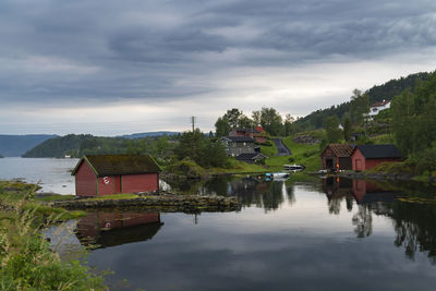 Houses by lake and buildings against sky