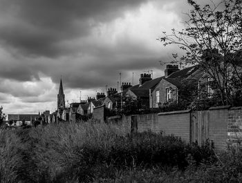 Houses in city against cloudy sky