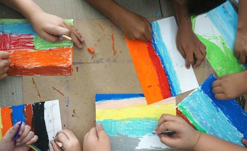 Low section of friends holding multi colored paper hand