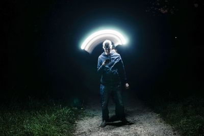 Man looking at illuminated light on field at night