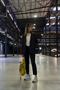 Businesswoman with backpack standing at railroad station