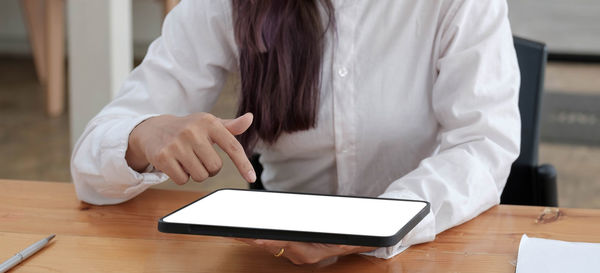 Midsection of woman using smart phone on table