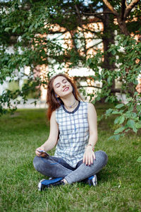 Beautiful smiling young woman sitting on grass