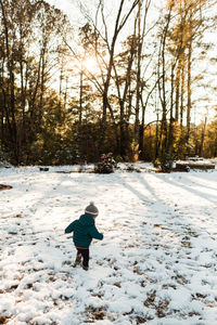 Rear view of child on snow covered landscape