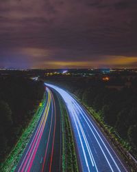 Light trails on road against sky at night