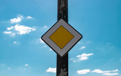 Low angle view of road sign against blue sky