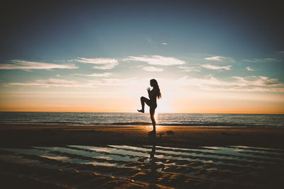 Silhouette person on beach against sky during sunset