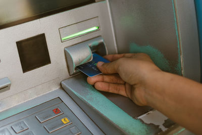 Cropped hand inserting credit card in atm machine