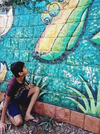 Full length of young man looking away against wall