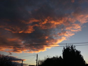 Low angle view of electricity pylon against cloudy sky