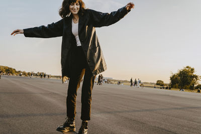 Young woman skating on road in park during sunset