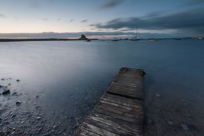 Pier over sea against sky during sunset