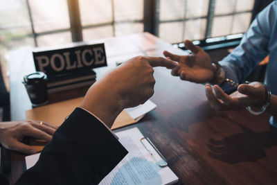 Midsection of man holding paper with text on table