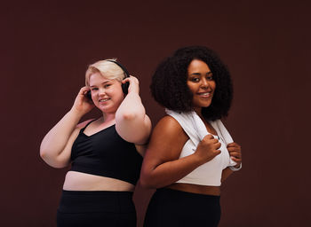 Portrait of females standing against colored background