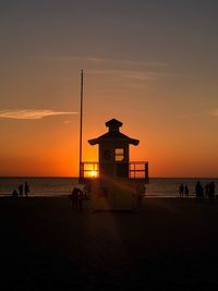 Silhouette people on beach against sky during sunset