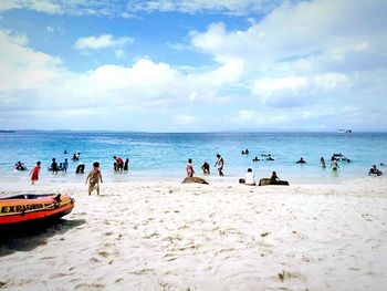 People enjoying on beach against sky