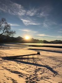 Scenic view of snow covered field against sky during sunset