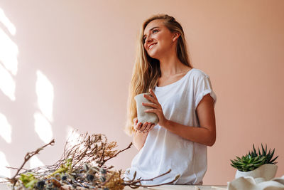 Young woman smiling while standing against plants