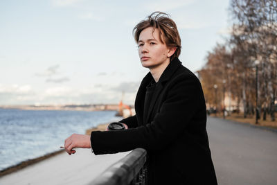 Young man looking away while holding cigarette 