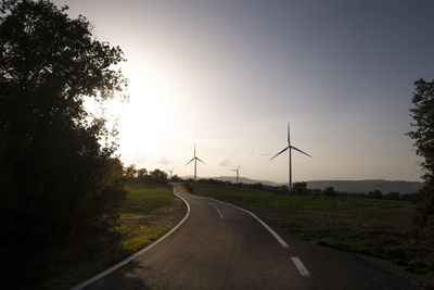 Road in agricultural fields with wind turbines generating clean electricity in catalonia spain