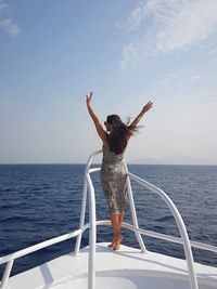 Full length of woman with arms raised against sea against sky