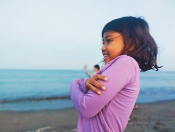 Side view of woman standing at beach against sky