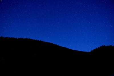 Low angle view of silhouette mountain against sky at night