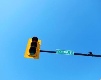 Low angle view of road sign against clear blue sky