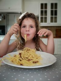 Portrait of girl having food in kitchen at home