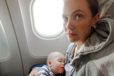 Baby is sleeping in plane with mom in her arms