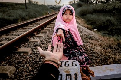 Low section of woman holding pink railroad tracks