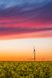 Windmill on landscape against sky during sunset