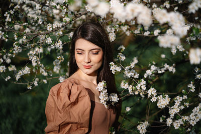 Portrait of beautiful woman standing by flowering plants