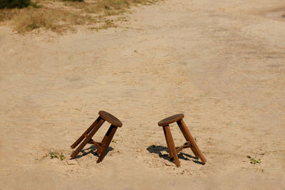 Empty stools on sand at beach