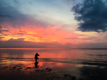 Silhouette man standing on beach against sky during sunset