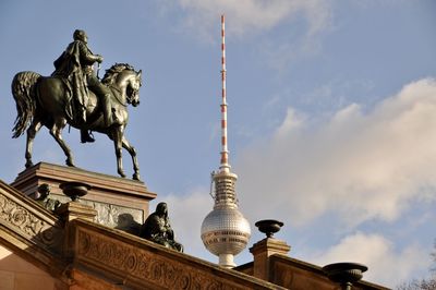 Low angle view of statues against cloudy sky