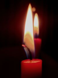 Close-up of lit candles in darkroom