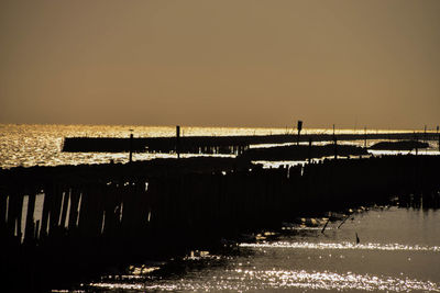 Silhouette pier over sea against clear sky during sunset