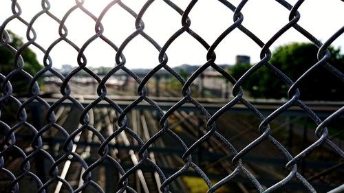 Railroad tracks seen through chainlink fence against clear sky