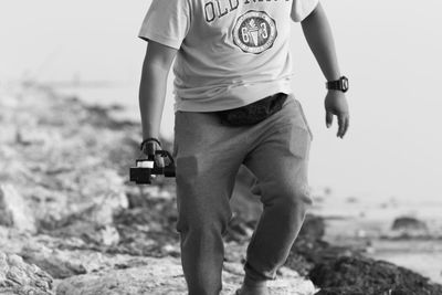 Low section of man standing on beach