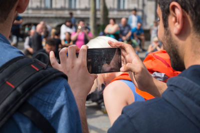 Cropped image of man photographing while standing in city